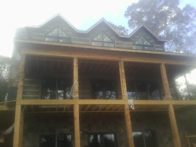 Dormers and porch framing on a large log home under construction — Roof Coating work by our crew in South Seaville