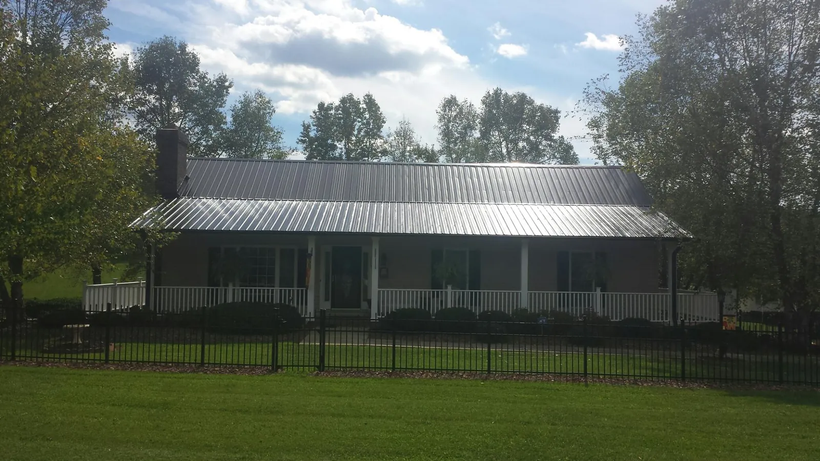 Gray metal roof on a brick ranch with a full width front porch — Gutter Guard Installation work by our crew in South Seaville