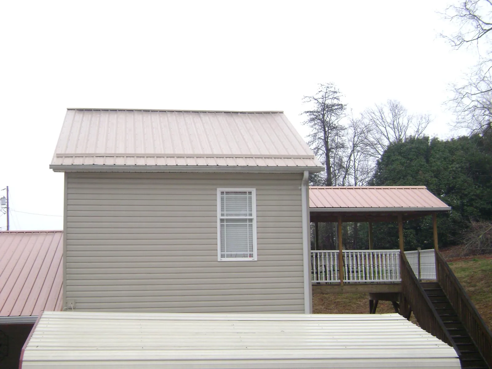Tan metal roofs on a two story addition and attached porch, from a Roof Replacement job in South Seaville